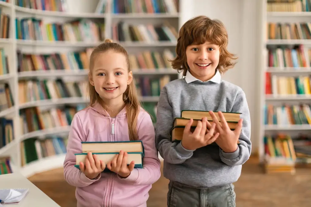 Two children in a library holding books.